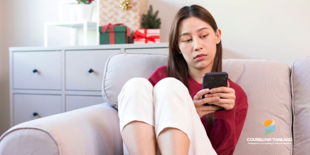 ผู้หญิงใส่เสื้อสีแดง เล่นมือถือบนโซฟา Holiday Blues